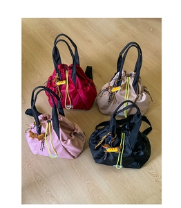 Detail view of colorful nylon drawstring backpacks with fashion labels and plush charms