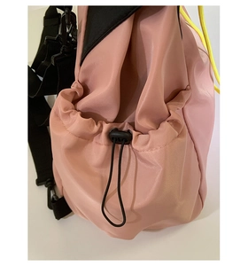 Detail of pink nylon drawstring bag featuring black spring buckle and yellow cord accents