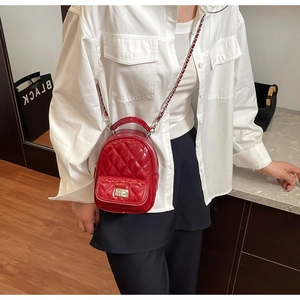 Detail of red quilted patent leather mini backpack with gold chain strap and turn-lock