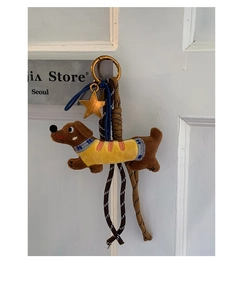Close-up of cute dachshund plush keychain with yellow knit sweater on white door