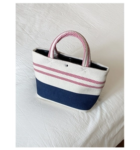 Close-up of contrast-colored canvas tote bag with red stripes and navy blue base detail