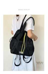 Detail of black nylon drawstring backpack with yellow cord and fashion label