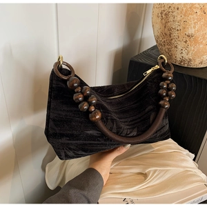 Detail of vintage beaded handle with brown wooden beads on black velvet handbag
