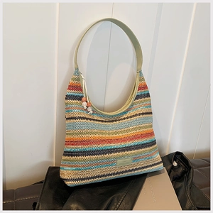 Detailed texture of rainbow stripe woven tote bag with green leather strap and beads