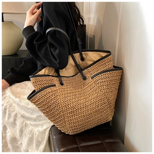 Close-up of woven straw tote bag with black leather handles and spacious interior pocket