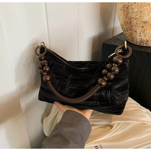 Detailed view of black velvet beaded handbag with vintage wood bead handle and leaf pattern