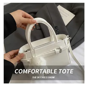 Détail d'un sac cabas blanc avec fermeture éclair argentée et pendentif en peluche