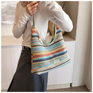 Detail shot of the rainbow striped woven tote bag featuring a leather logo and beaded zipper