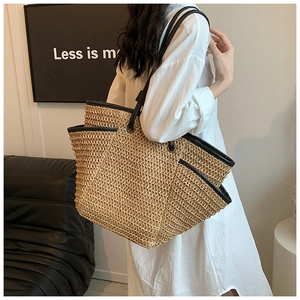Detailed texture of hand-woven straw tote bag with black leather trim and handle