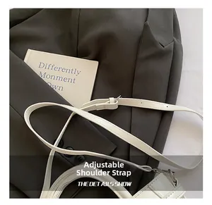 Détail de la bandoulière réglable en cuir blanc avec boucle argentée sur le sac