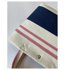 Close-up of woven canvas tote texture with blue stripes and silver metal buckle