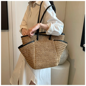 Close-up of the woven straw texture and black leather strap on this vacation tote bag