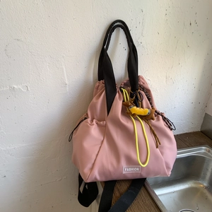 Pink drawstring backpack featuring black handles and a yellow dachshund plush charm accessory