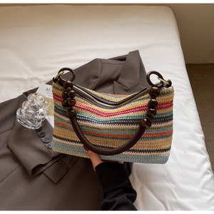 Close-up of a colorful woven bag with dark brown wooden bead handles and a metal zipper