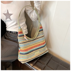 Detail of colorful rainbow woven tote bag with sage green leather strap and beaded charm