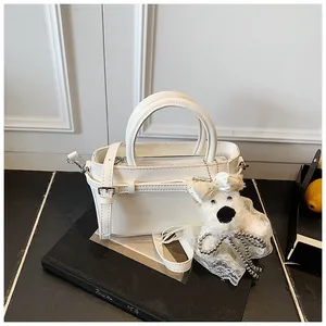 Détail d'un sac seau en cuir blanc avec un pendentif ours en peluche et une poignée