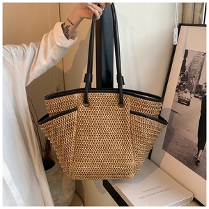 Detail of hand-woven straw tote with black leather trim and large side pocket design