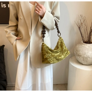 Close-up of olive green velvet handbag featuring vintage brown beaded shoulder strap