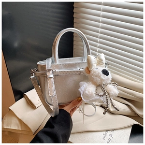 Détail du sac seau argenté métallisé avec pendentif chiot en peluche et texture gaufrée