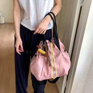 Detailed close-up of pink nylon drawstring backpack with black handles and cute dog charm