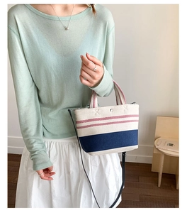 Detail of canvas striped tote bag featuring red white blue patterns and metal buckle