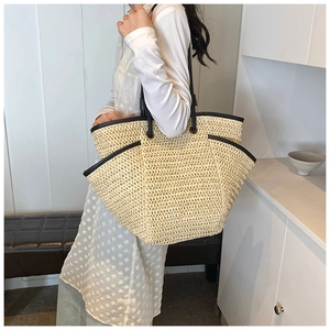 Close-up of a large straw tote bag with black trim and handles for summer beach vacations