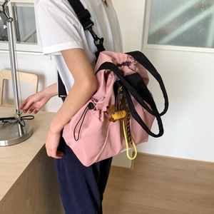 Detail view of pink nylon drawstring backpack with cute dog plush charm and fashion tag