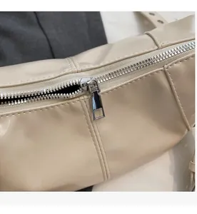 Dettaglio della cerniera argentata e delle cuciture sulla borsa in pelle beige