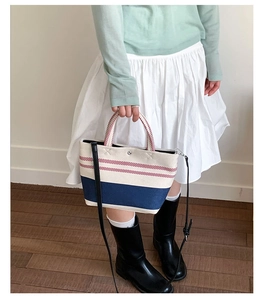 Lifestyle shot of a red and blue striped canvas tote bag worn with a casual outfit