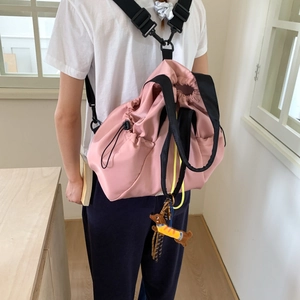 Detail of pink nylon drawstring backpack featuring a cute dog charm and wide black straps