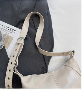 Dettaglio borsa a spalla in pelle bianco panna con occhielli argentati sulla tracolla larga