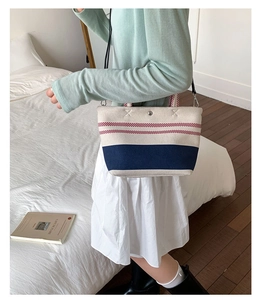 Detail of striped canvas tote bag showing metal snap closure and D-ring for strap