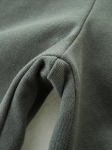 Detailed close-up of olive green knit cotton fabric and durable double-stitch seam work