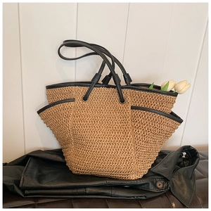 Detail of hand-woven straw tote with black leather trim and dual side pockets