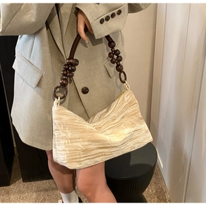 Close-up of beige pleated fabric texture and vintage brown wooden bead handle on handbag