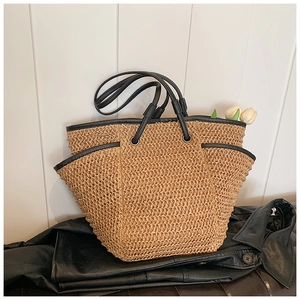 Detail of woven straw tote bag featuring black leather trim and functional side pockets