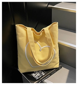 Détail du sac cabas en toile jaune avec broderie cœur blanc et accents métalliques