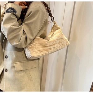 Detail of champagne pleated shoulder bag featuring retro dark brown wooden bead strap