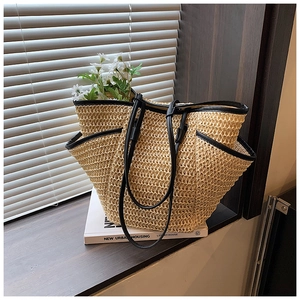 Detail of straw woven tote bag with black faux leather trim on a sunlit windowsill