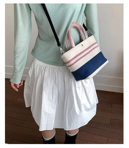 Detail of nautical canvas tote with red stripes and woven red check handles