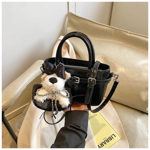 Détail du sac seau noir brillant avec un joli pendentif chiot en peluche blanche