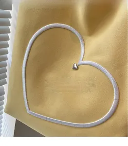 Gros plan du sac fourre-tout en toile jaune avec broderie cœur blanc et boucle métallique