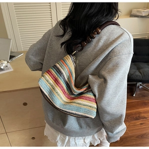 Detail showing colorful rainbow stripe knit pattern and dark wooden bead handles of hobo bag