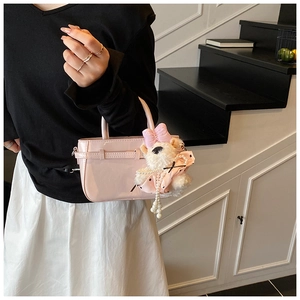 Détail du sac seau en cuir verni rose avec un ours en peluche et une chaîne en perles