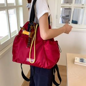 Detail of red waterproof nylon drawstring backpack with fashion label and puppy charm