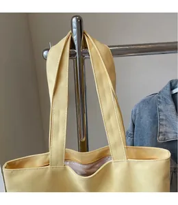 Détail du cabas en toile jaune clair avec longues bandoulières et coutures renforcées