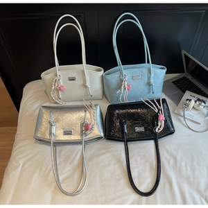Detail view of four glossy underarm tote bags in beige, blue, silver, and black finishes