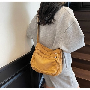 Detail view of mustard yellow canvas bag with multiple zipper compartments and strap