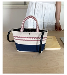 Detail of red and white checkered canvas tote bag with navy blue base and leather strap