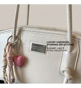 Close-up of off-white wrinkled leather handbag with silver logo plate and heart charm